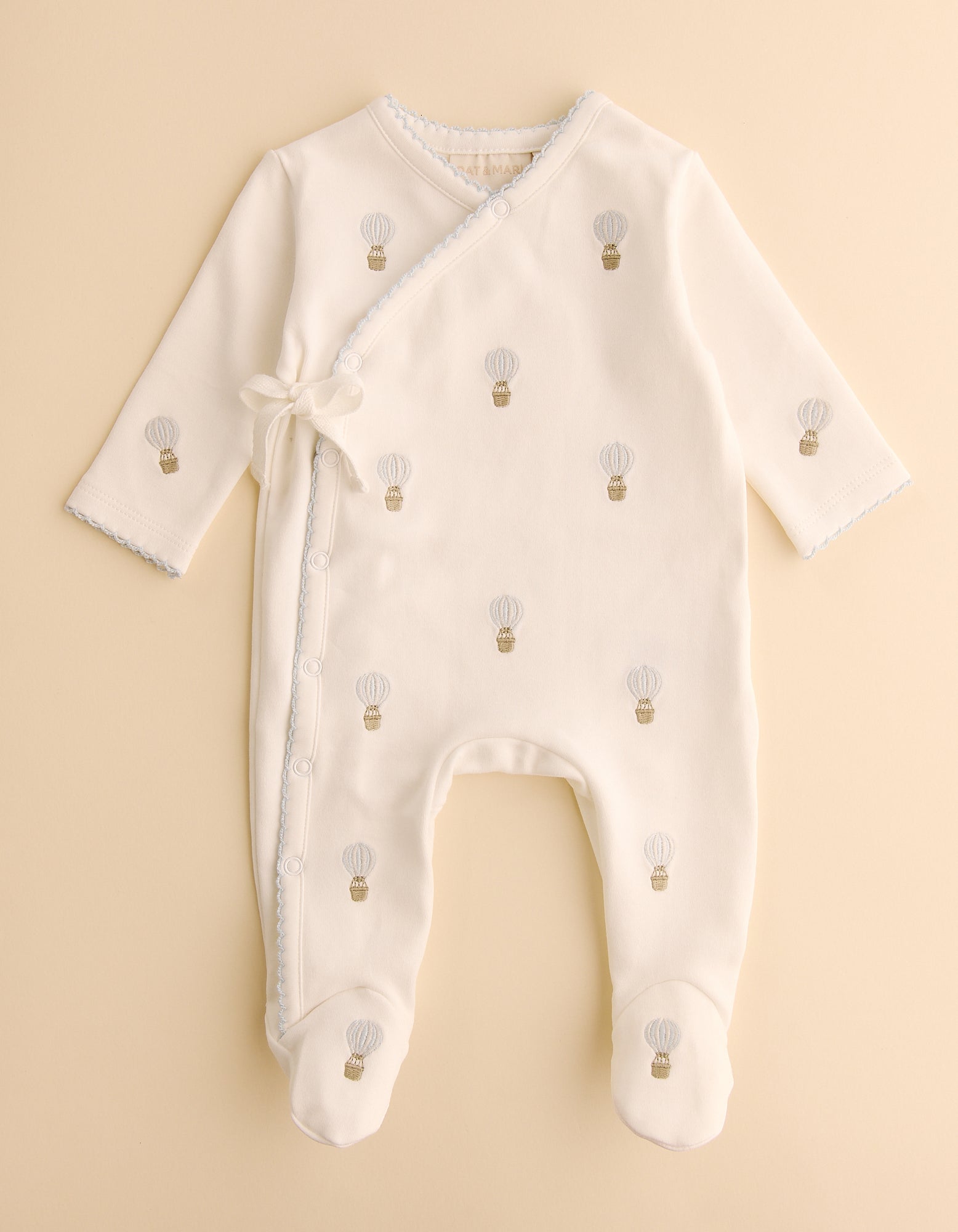 Baby onesie with hot air balloon pattern on a beige background