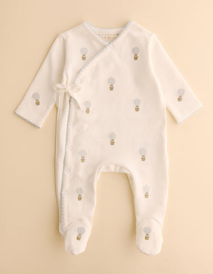 Baby onesie with hot air balloon pattern on a beige background