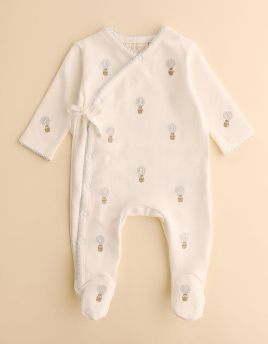 Baby onesie with hot air balloon pattern on a beige background